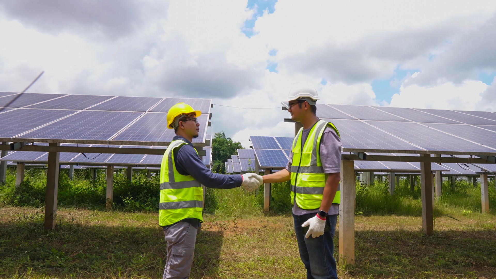 Two asian engineers shaking hands after  installing solar panels . Solar energy clean and green alternative energy. Unity and teamwork.